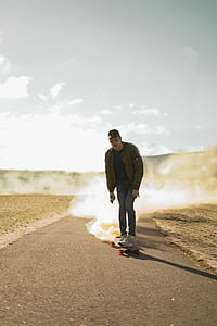 man riding on longboard with smoke under gray sky thumbnail