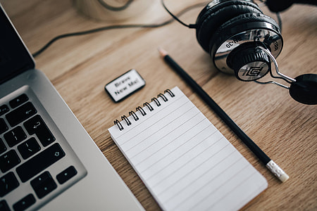 MacBook Pro with headphones on a wooden desk thumbnail