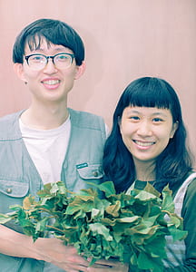 man and woman holding green leaf plants thumbnail