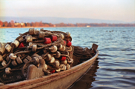 selective focus photography of boat with fish net on calm body of water at daytime thumbnail