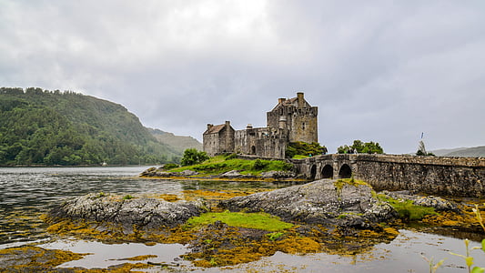 castle surrounded by body of water near mountain thumbnail