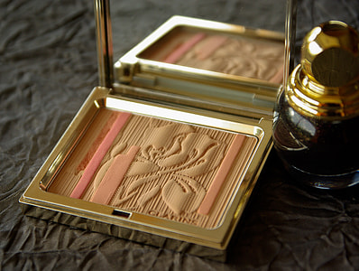pink and beige compact powder case beside fragrance bottle thumbnail