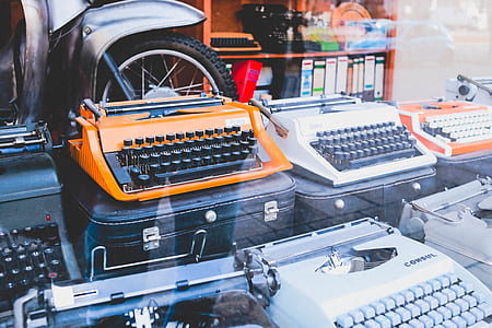 white and orange typewriter machines on black cases thumbnail