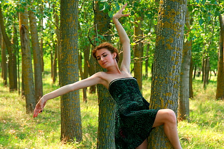 woman wearing black strapless dress making a pose in a forest thumbnail