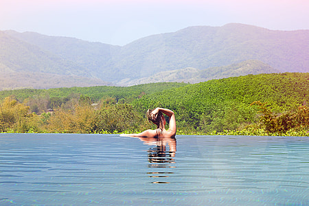 woman in body of water facing the mountains during day thumbnail