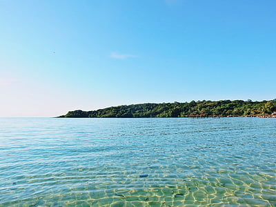 calm body of blue water near green covered mountain thumbnail