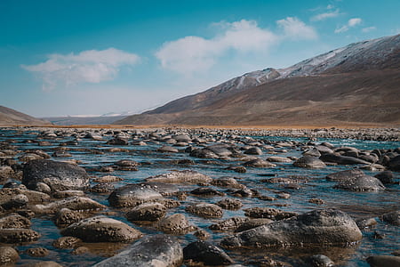body of water with stones in front of mountain thumbnail