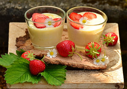 two drinking glasses beside strawberries on brown wooden surface thumbnail