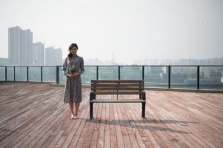 woman holding flower bouquet beside brown wooden bench thumbnail