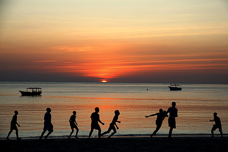 group of people playing at beach during sunset thumbnail