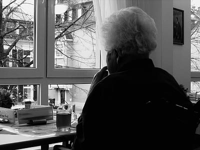 grayscale photo of person sitting near window thumbnail