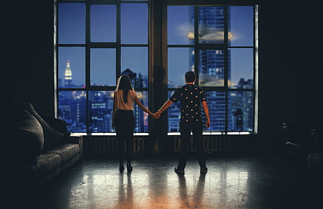 man and woman holding hands facing glass window during dawn thumbnail