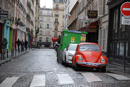 red Volkswagen beetle parked near pedestrian thumbnail