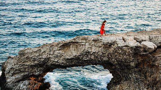 woman walking on gray rock formation thumbnail