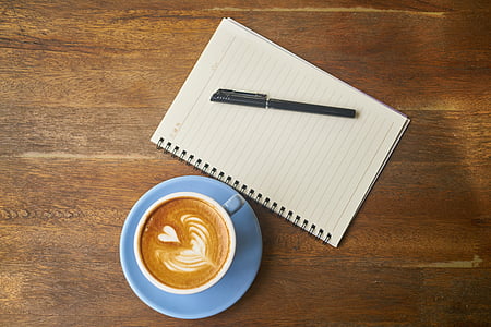 white and blue ceramic coffee mug and saucer on brown wooden surface thumbnail