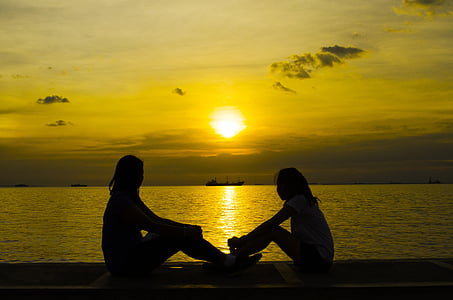 person sitting on sidewalk during sunset thumbnail