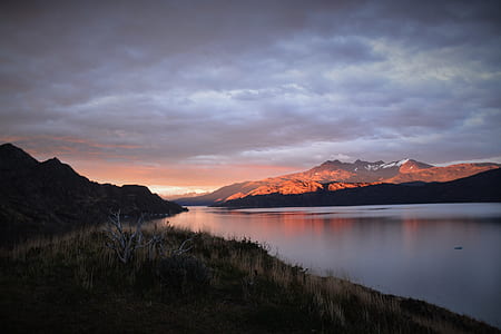body of water between mountain under white cloudy sky thumbnail