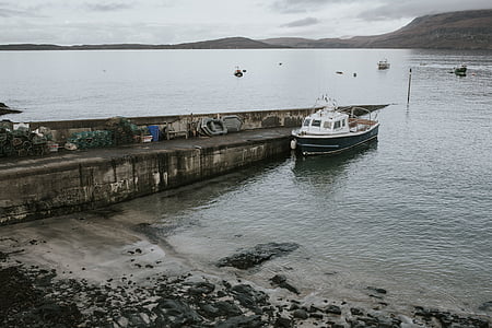 white motorboat beside concrete wall at daytime thumbnail