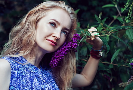 woman wearing blue and white floral sleeveless tops holding purple cluster flower thumbnail