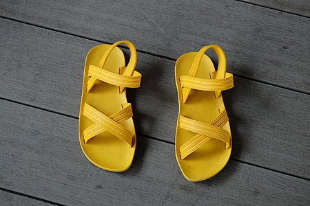 pair of yellow flat sandals on wooden surface thumbnail