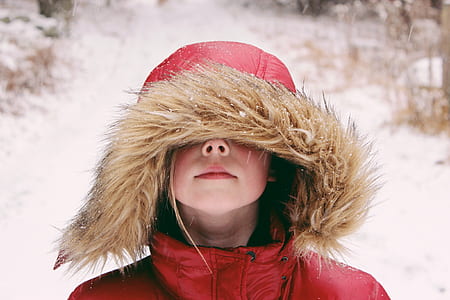 girl wearing red hooded winter jacket while standing on snow field thumbnail