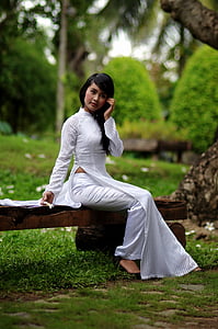 woman in white traditional dress sitting on bench during daytime thumbnail