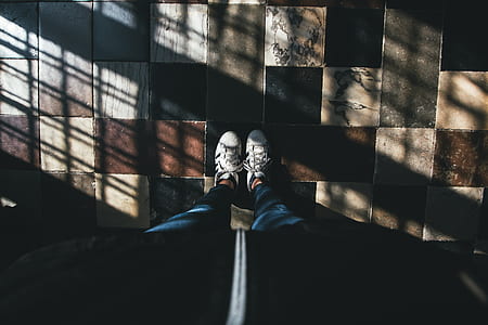person in blue jeans wearing white sneakers inside lighted room thumbnail