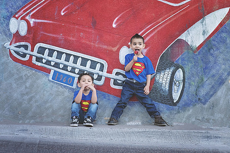 two boy eat lollipop while leaning on wall thumbnail