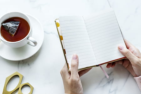 person opening notebook near mug with beverage thumbnail
