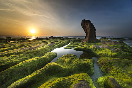aerial photography of green and brown rock formation near body of water at golden hour thumbnail