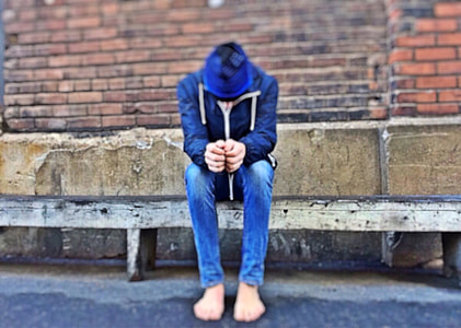 shallow focus photography of person in blue hoodie jacket and blue jeans sitting on bench seat during daytime thumbnail