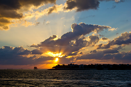 sunset over horizon with ship and island silhouettes thumbnail