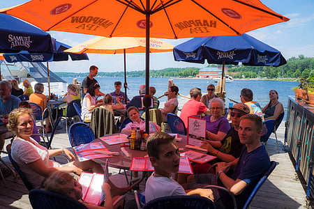 group of people sitting on chair under patio umbrella thumbnail