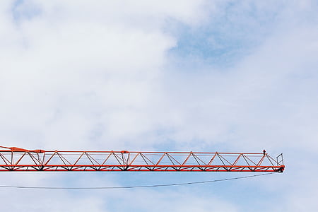 orange tower crane under white cloudy sky thumbnail