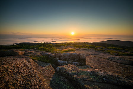 brown boulder near sea during golden hour thumbnail