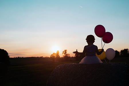 girl sitting on stone holding balloons thumbnail
