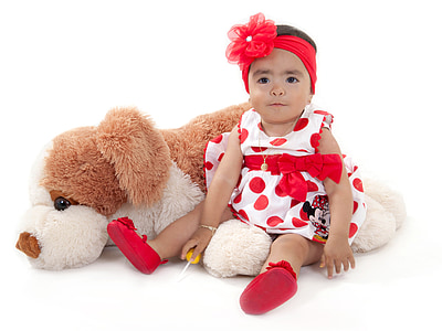 baby wearing white and red polka-dot dress beside dog plush toy thumbnail