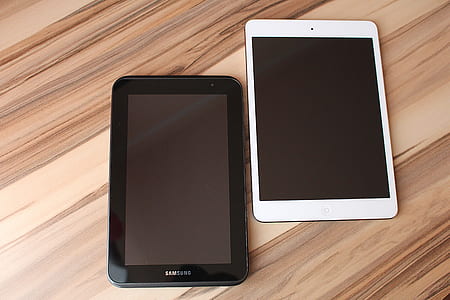 black Samsung Galaxy Tab beside white iPad on brown wooden desk thumbnail
