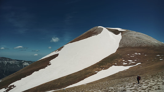 person hiking along brown and white mountain thumbnail