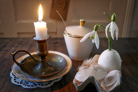 lighted candle on table near white flower thumbnail