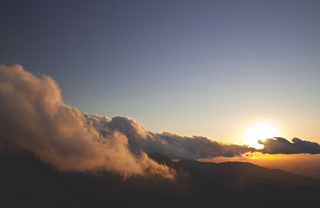 silhouette photo of mountain under white clouds and blue sky at golden hour thumbnail
