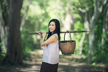 woman holding stick with basket on her back thumbnail