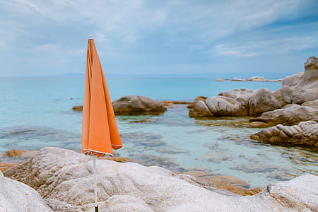 orange parasol on rock near ocean during blue hour thumbnail