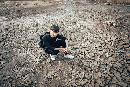 Man Wearing Long-sleeved Shirt Sitting on Empty Area thumbnail
