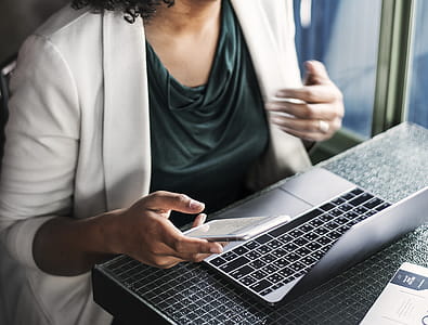 Woman Sitting Holding Smartphone And Facing Laptop thumbnail