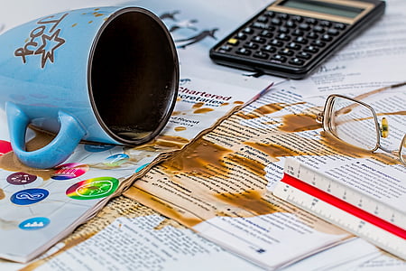 spill brown liquid on paper beside eyeglasses, mug and calculator thumbnail