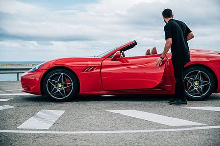 A young man in black dress getting into a red convertible sports car thumbnail
