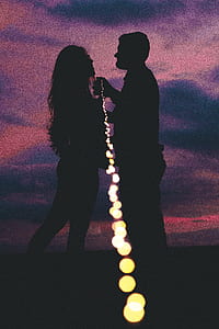 silhouette of woman and man holding string light during nighttime thumbnail