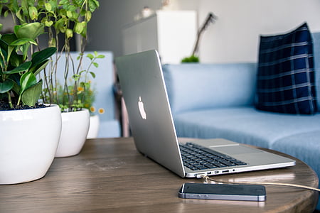 silver MacBook Pro beside space gray iPhone 5s on brown wooden table thumbnail