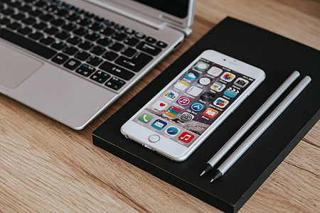 Silver Acer laptop, a white Apple iPhone and a notepad on a wooden desk thumbnail
